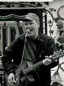 Man singing into a microphone and holding a guitar