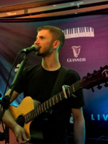Man singing into a microphone with a guitar