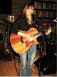 Women singing into a microphone and holding a guitar