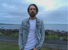 Man standing on grass with the sea in the background